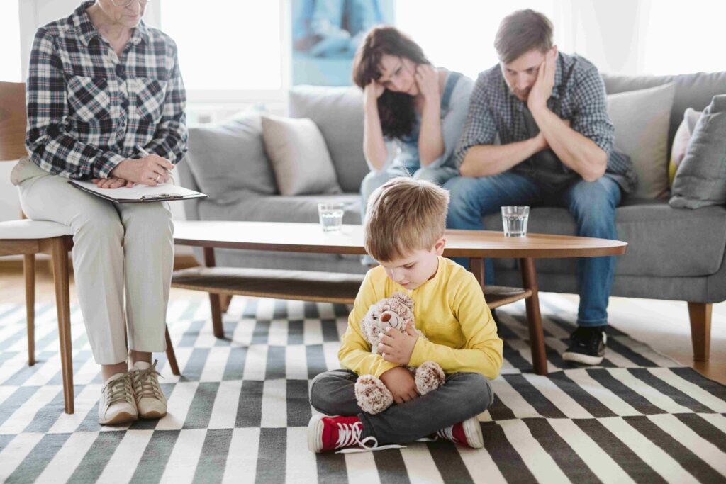 Lonely sad boy sitting on a floor on a family psychotherapy session